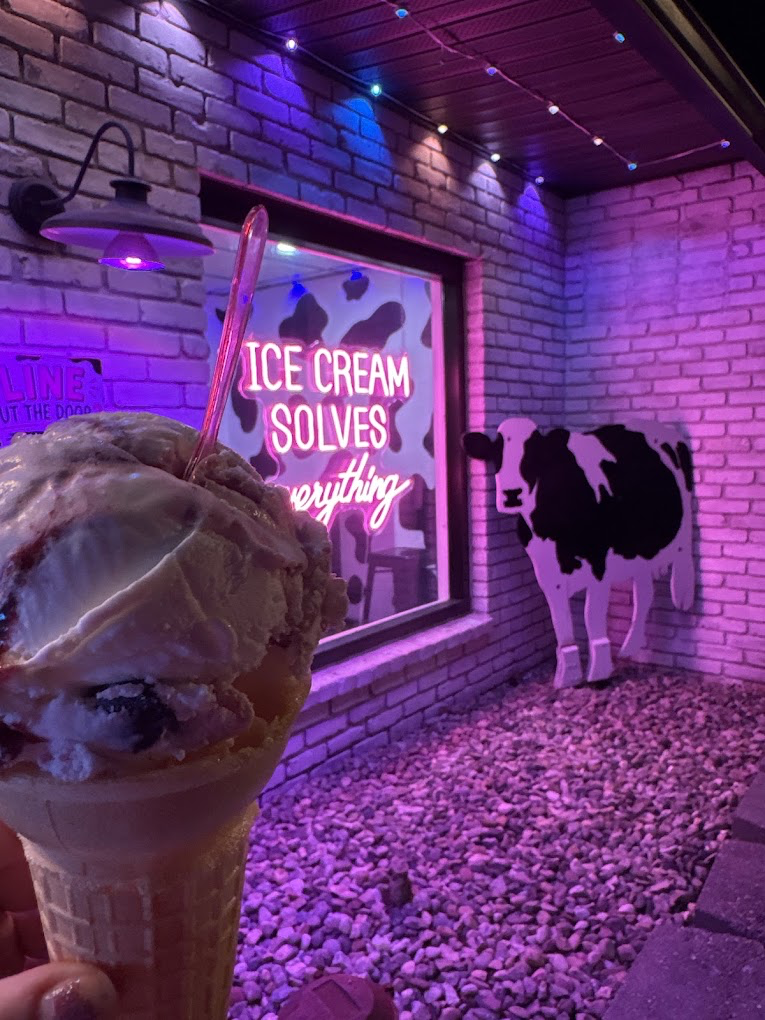 Neon patio with 'Ice cream solves everything' sign and a cow cutout